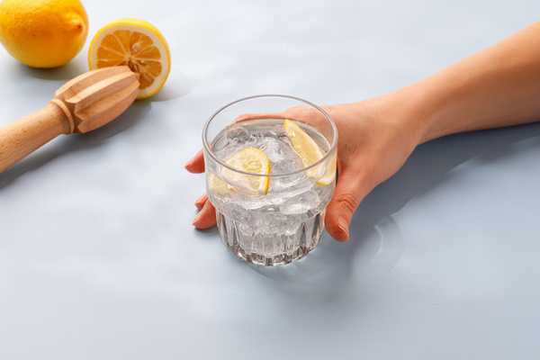 Gelas air dan irisan lemon di meja terang